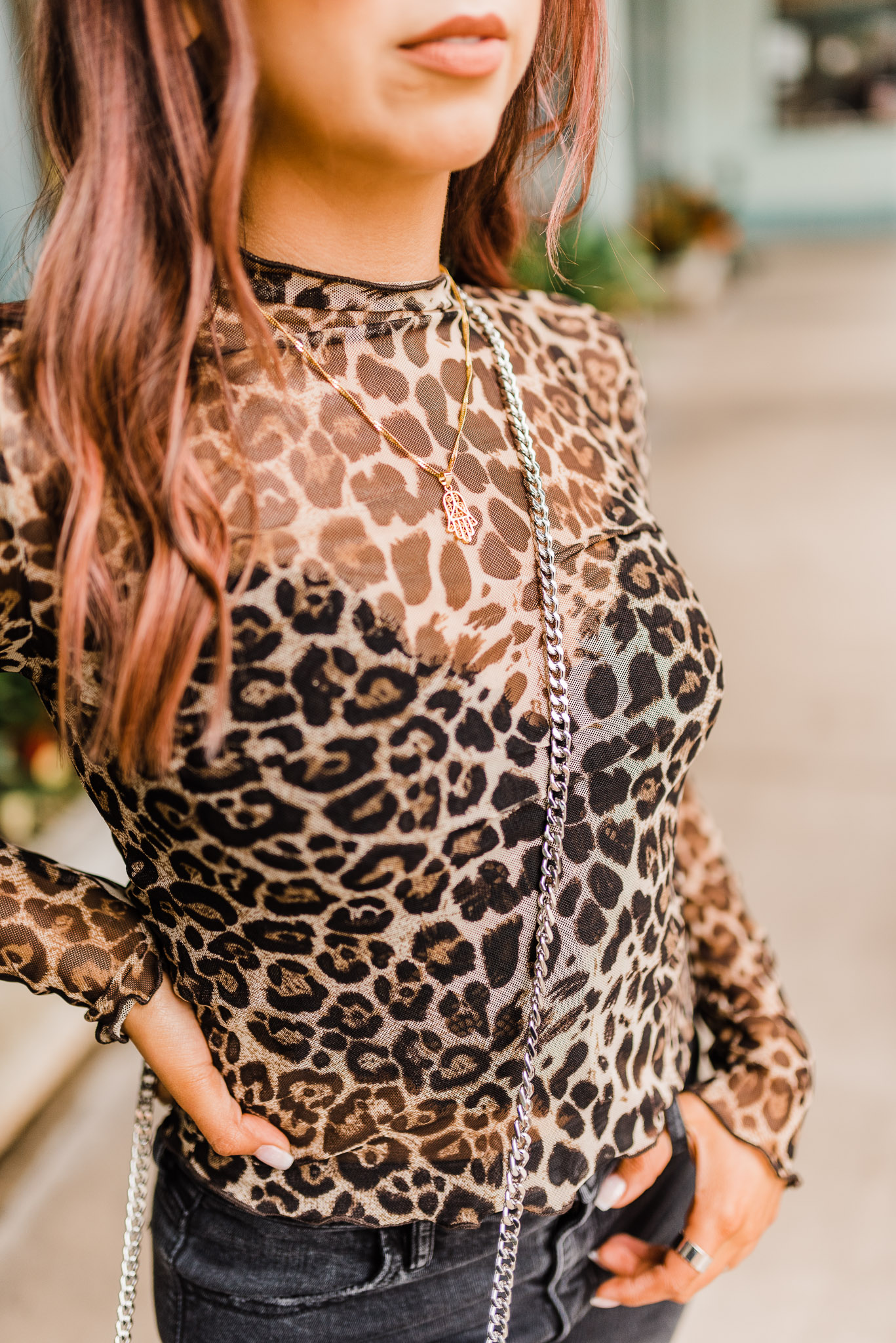 Female fashion blogger detail shot. Cheetah print shirt with chain link purse.