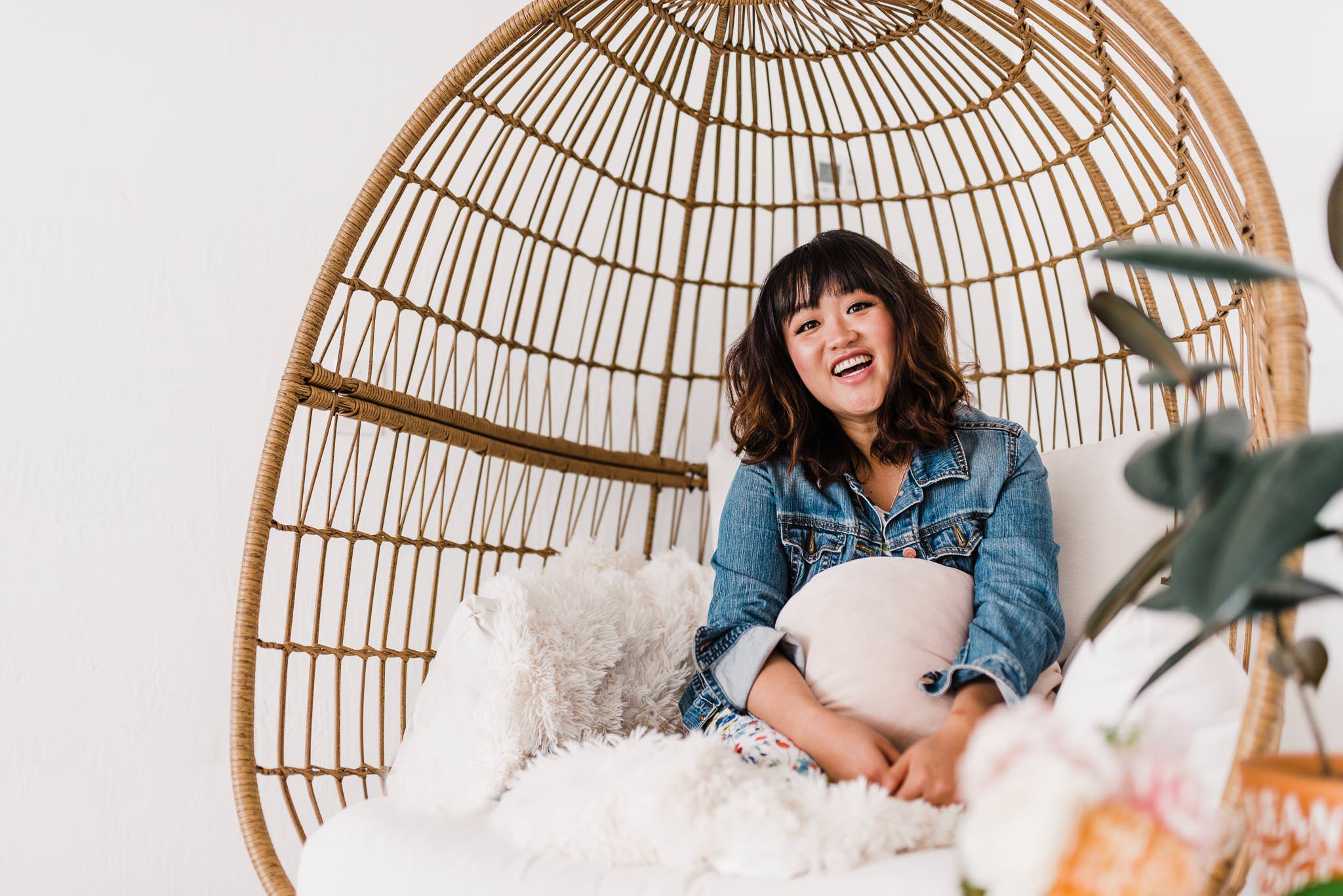Smiling woman sitting in comfy boho chair with pillows.