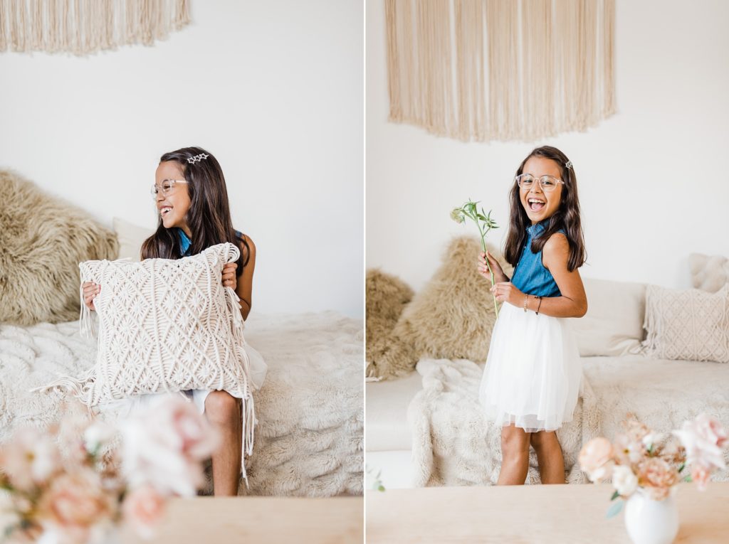 A little girl holding a flower and a pillow.