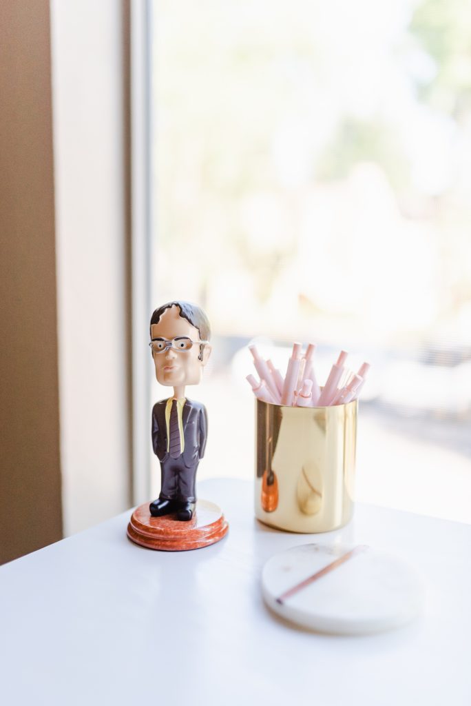 Close up of a Dwight Schrute bobblehead and a can of pink pens.