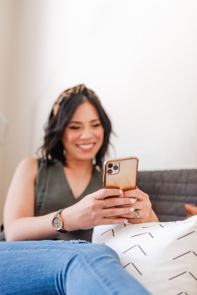 Woman sitting on a couch using her iPhone 11 Pro.