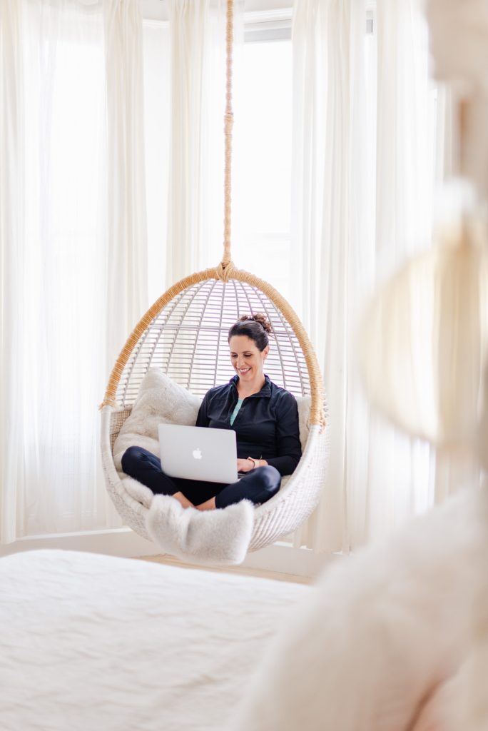 branding photo of a woman sitting in a hanging egg chair.