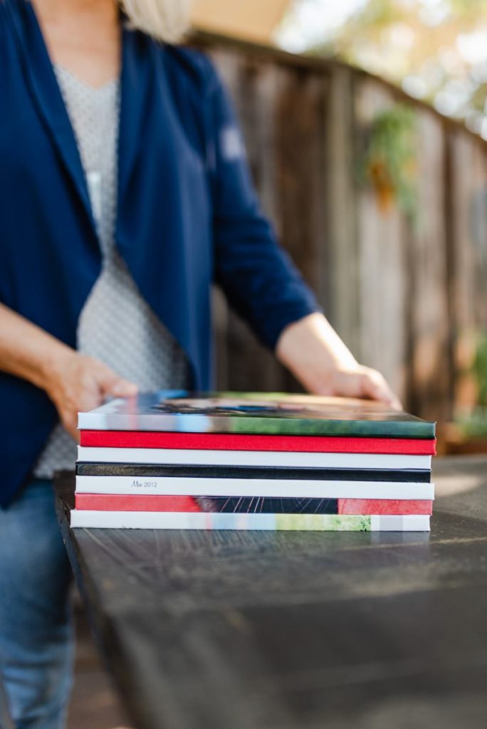 woman in blue cardigan putting a stack of books on a table