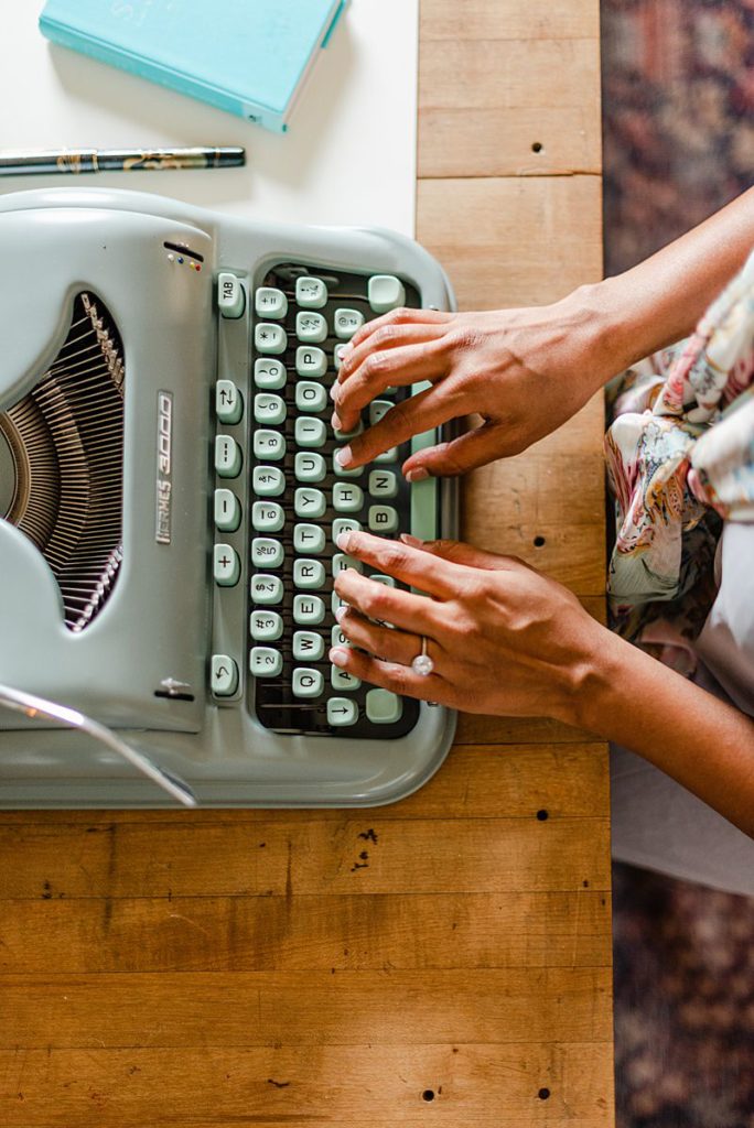 top view of a typewriter with a woman's hands typing