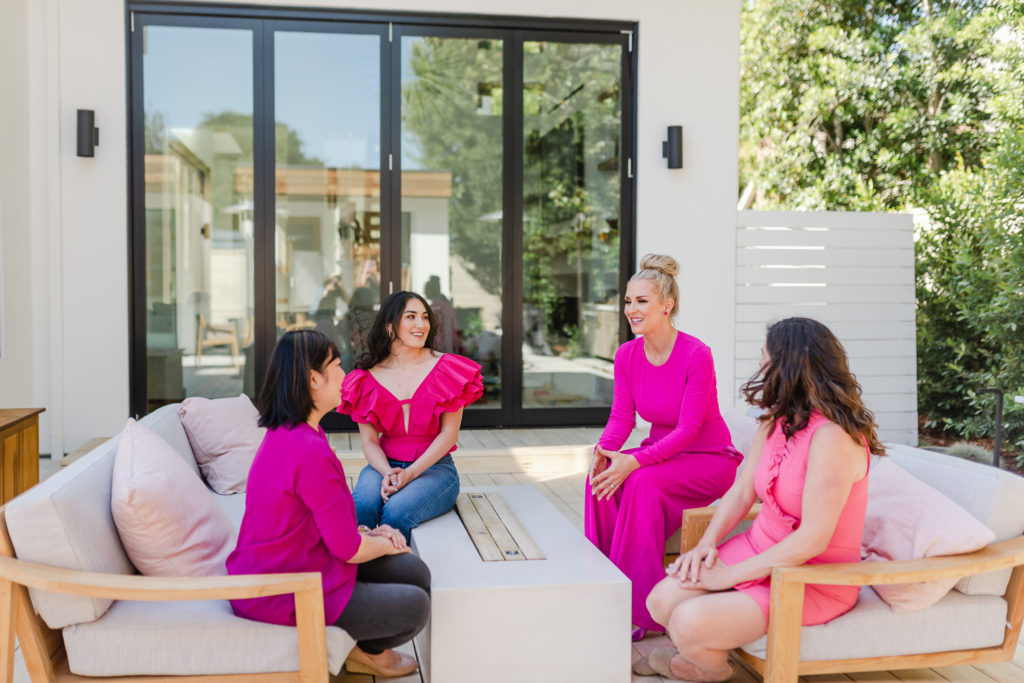group of 4 women wearing various shades of pink on an outdoor living area