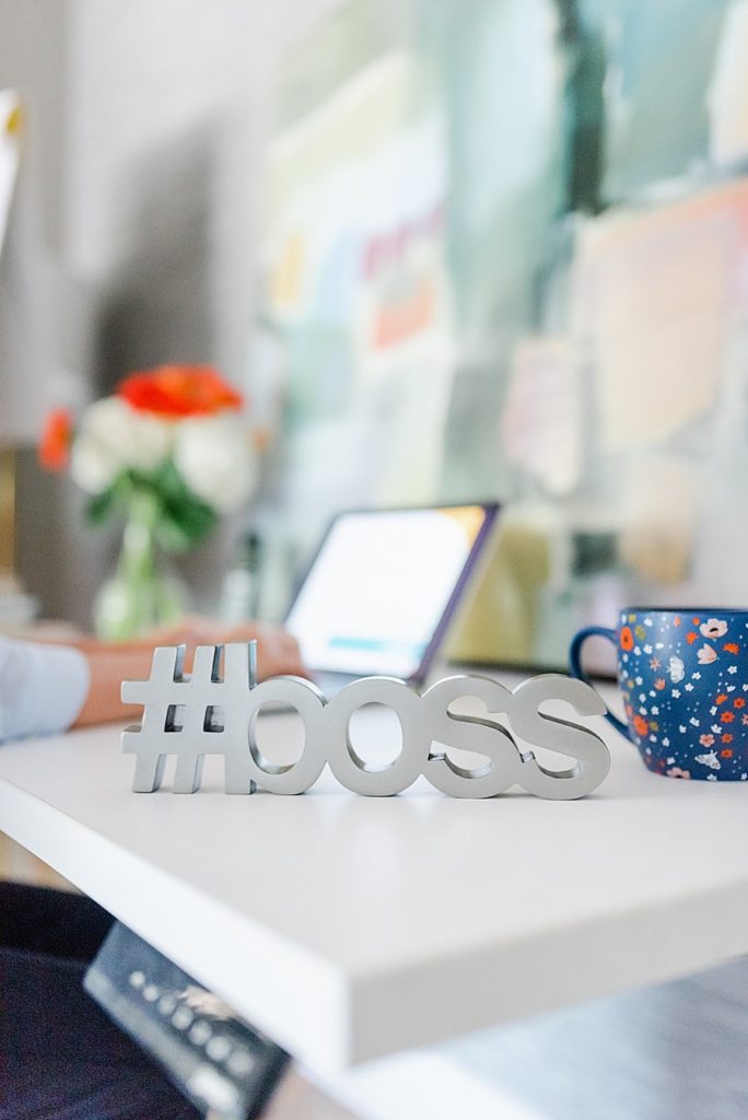 #boss decoration on top of desk. a blue mug is on the right of the figure.