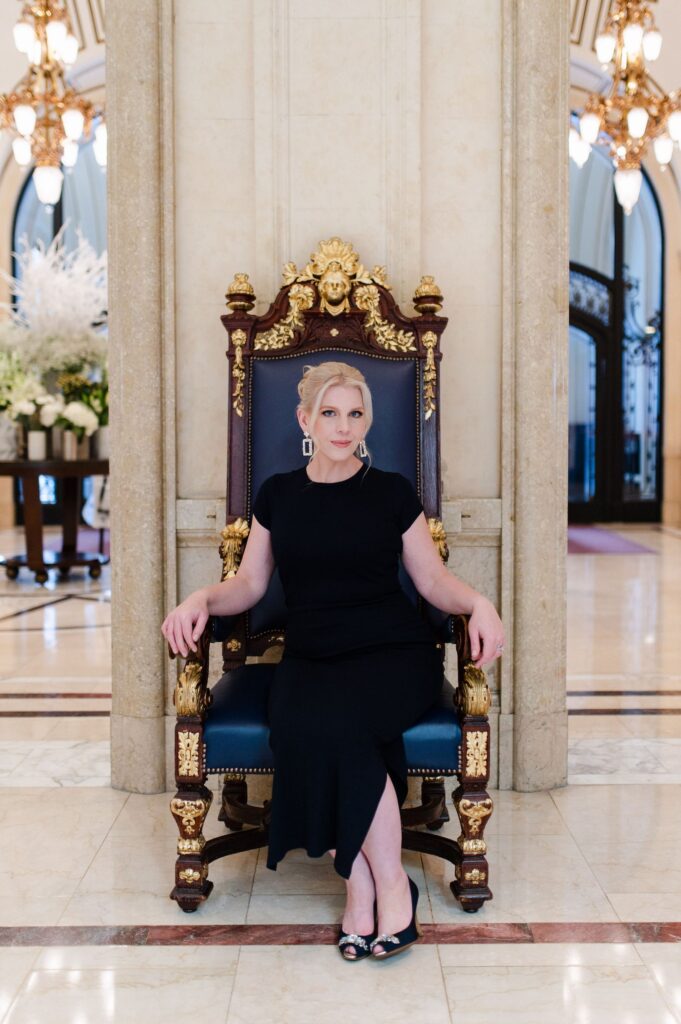woman in a blue dress sitting on a grand throne chair