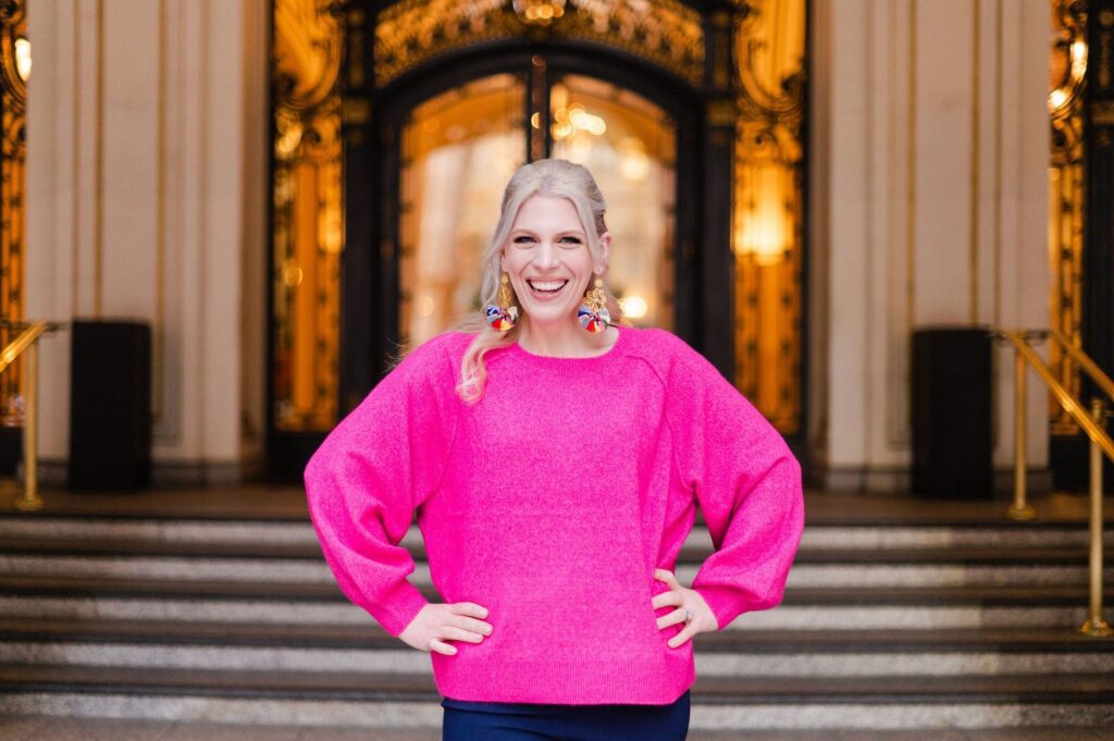 woman in a hot pink sweater standing and laughing