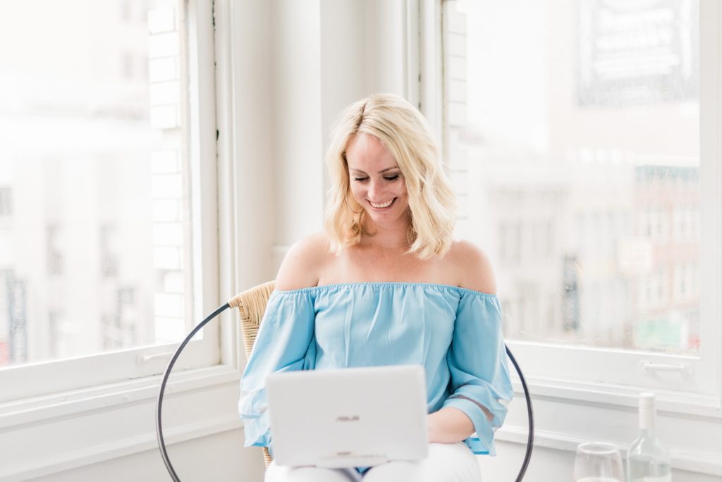 Woman wearing a light blue shirt on her laptop in a white room