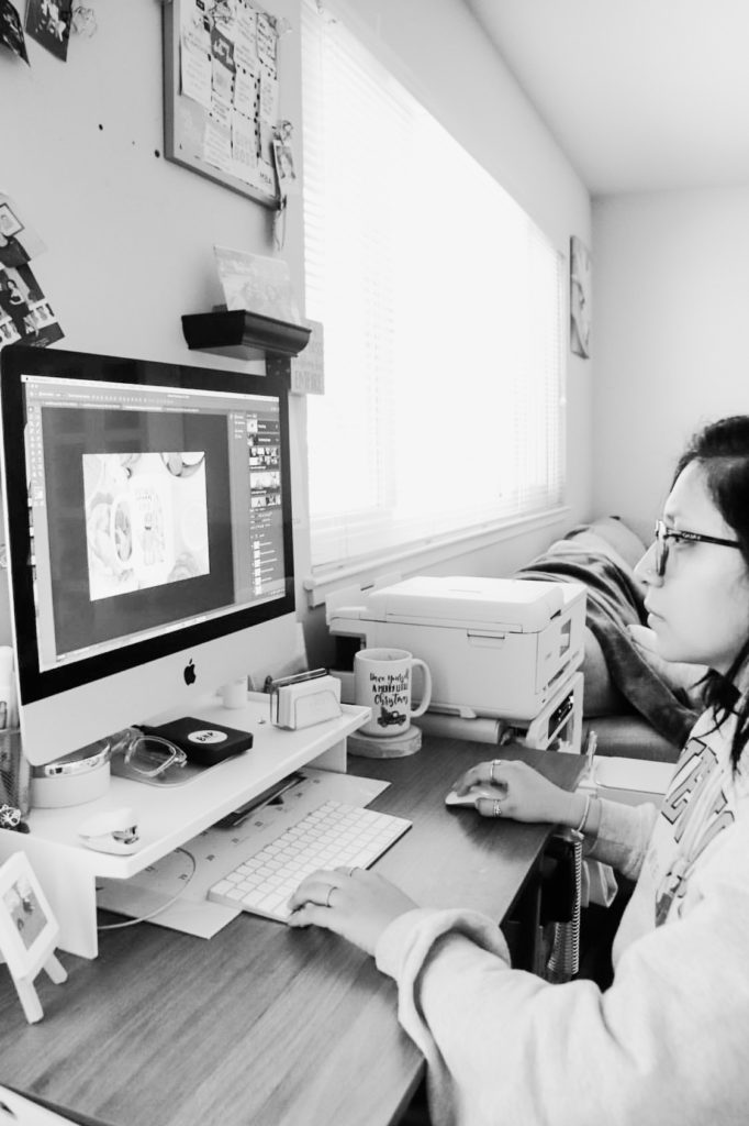 Black and white photo of a woman sitting at her computer, working on a design.