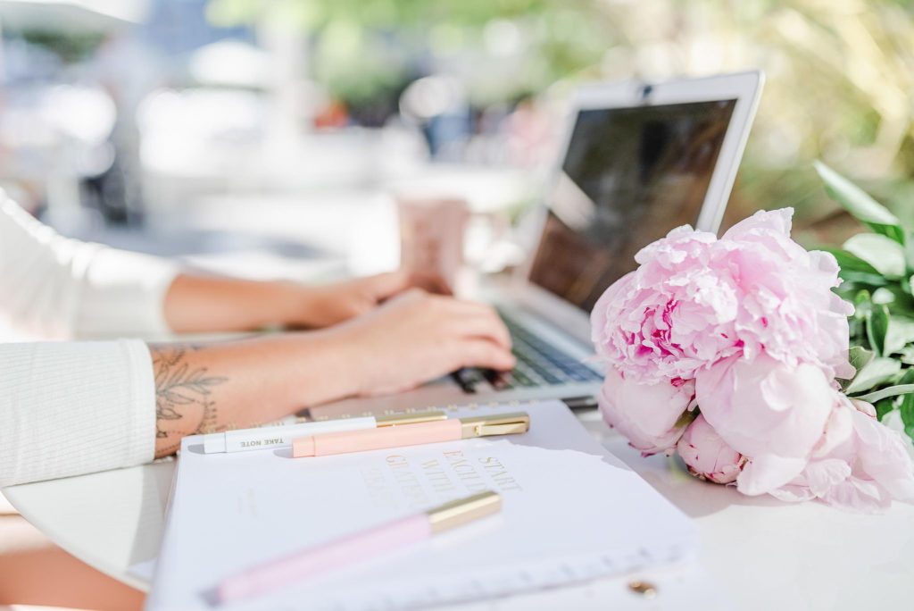 flat lay of a MacBook, iPhone, and pink accessories