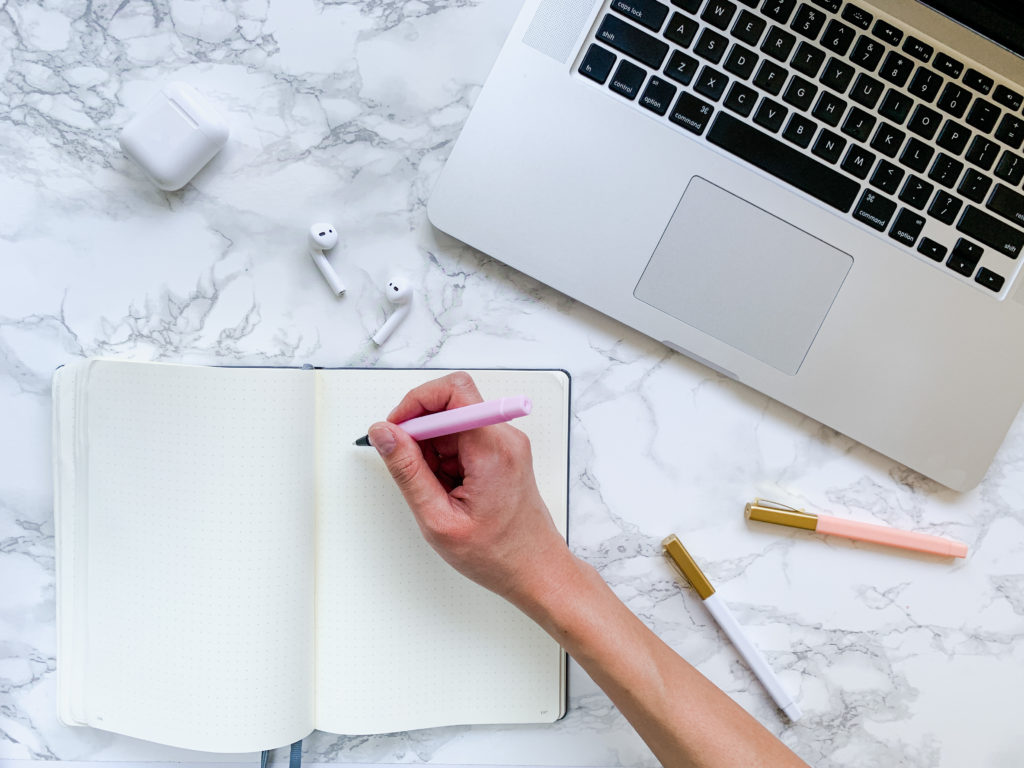 desk flat lay with a computer and writing in a journal