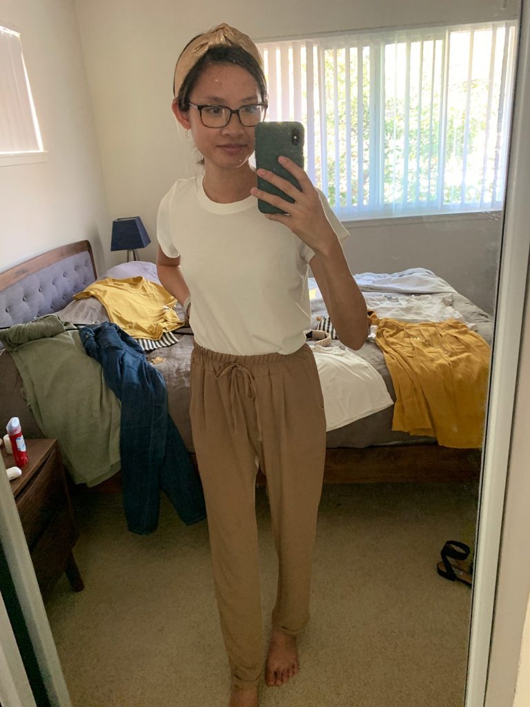 mirror selfie of a woman wearing a white t-shirt and soft tan pans.