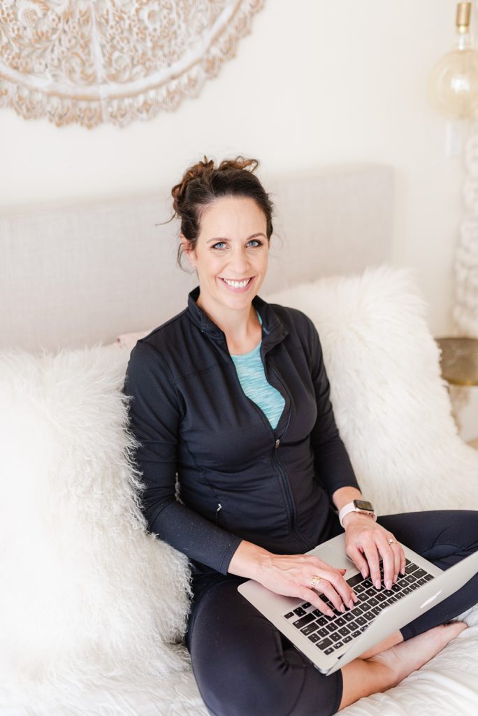 branding photo of a woman sitting on a bed on her laptop.