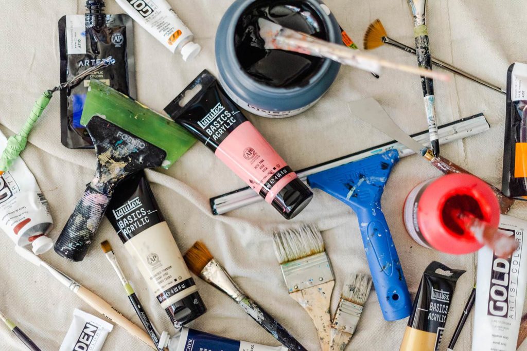 Flat lay image of artist tools. Paint, brushes, and squeegees.