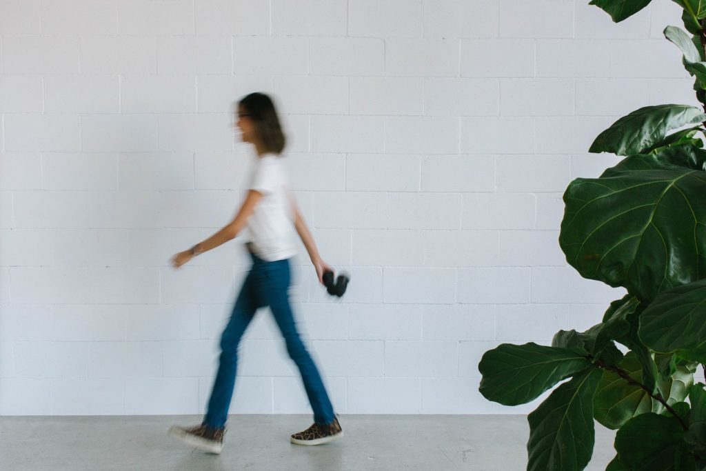 motion blur of woman walking across white wall