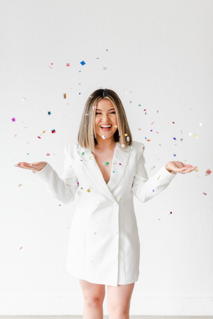Woman wearing a white blazer dress and throwing confetti