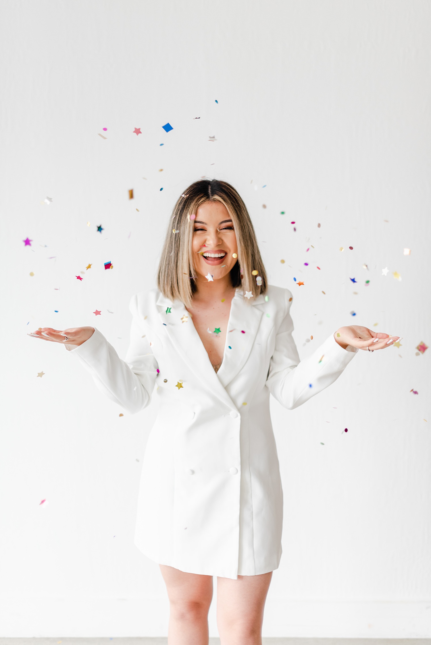 Woman wearing a white blazer dress and throwing confetti