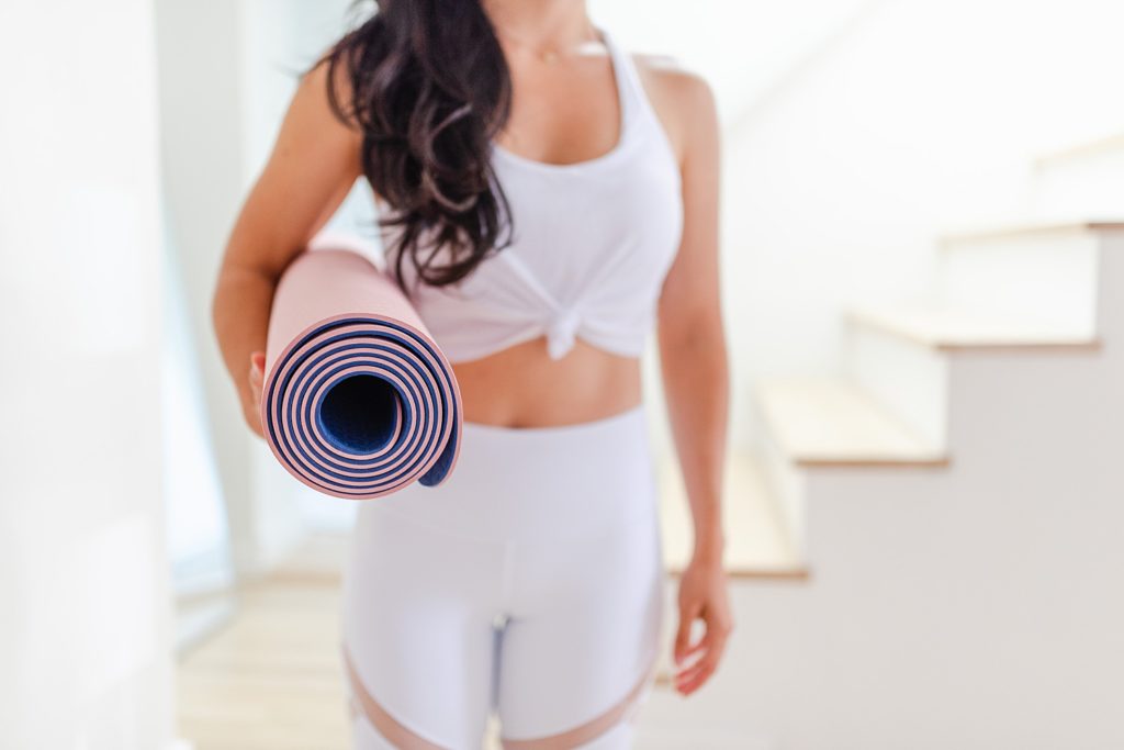 Woman holding a rolled up yoga mat.