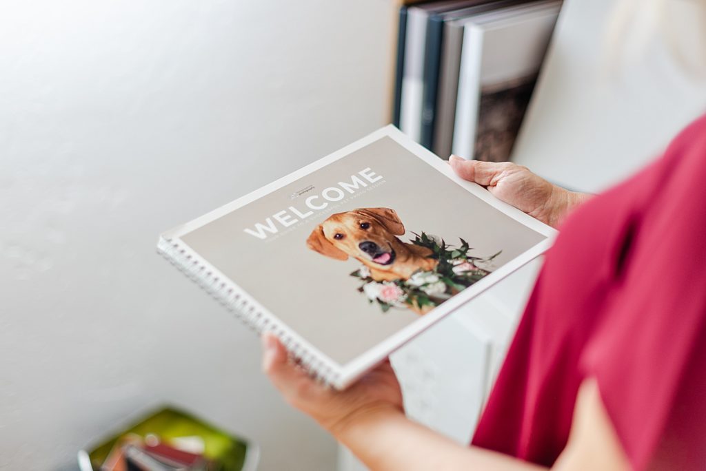hands holding a notebook with the photo of a brown dog on the cover with the word "welcome" on top