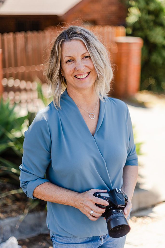 Tonya Perme, pet photographer, wearing blue blouse and holding her camera