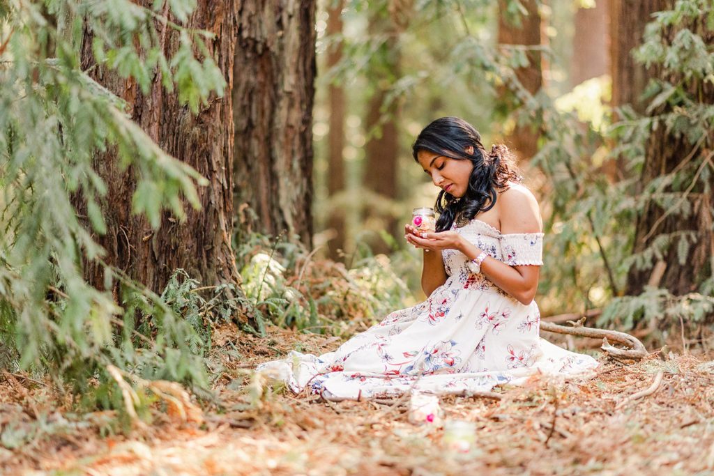 woman in white dress is sitting on the forest ground