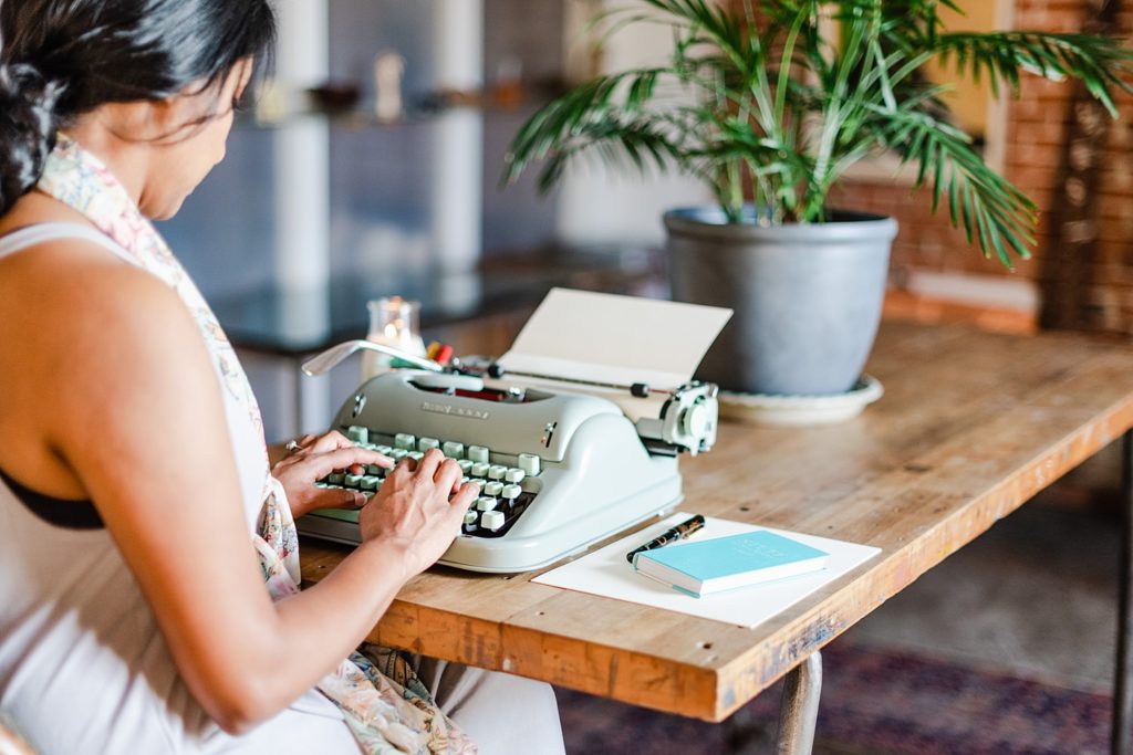 woman typing on a typewriter on top of a wooden table
