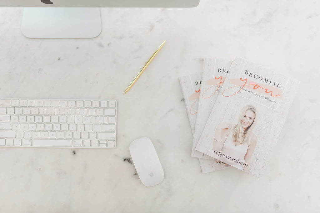 white flatlay photo of a keyboard, mouse, and a couple of books with a woman on the cover