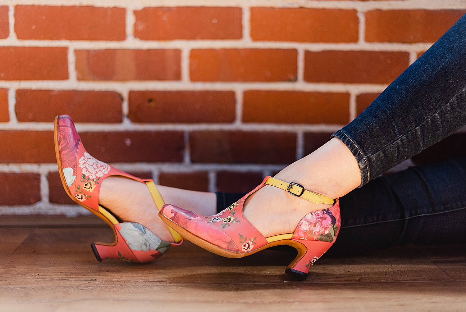 woman's feet wearing a coral-colored, floral shoes with two-inch heels