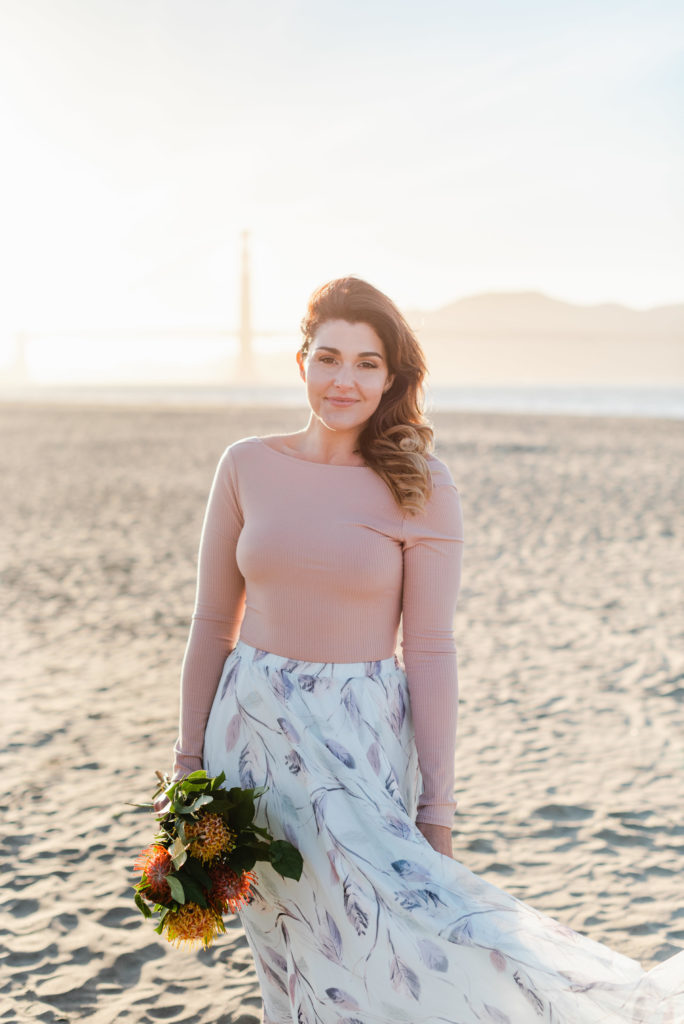 woman holding a bunch of flowers standing on a beach