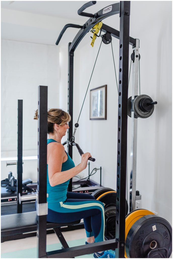 woman in workout clothes using a lat pulldown machine