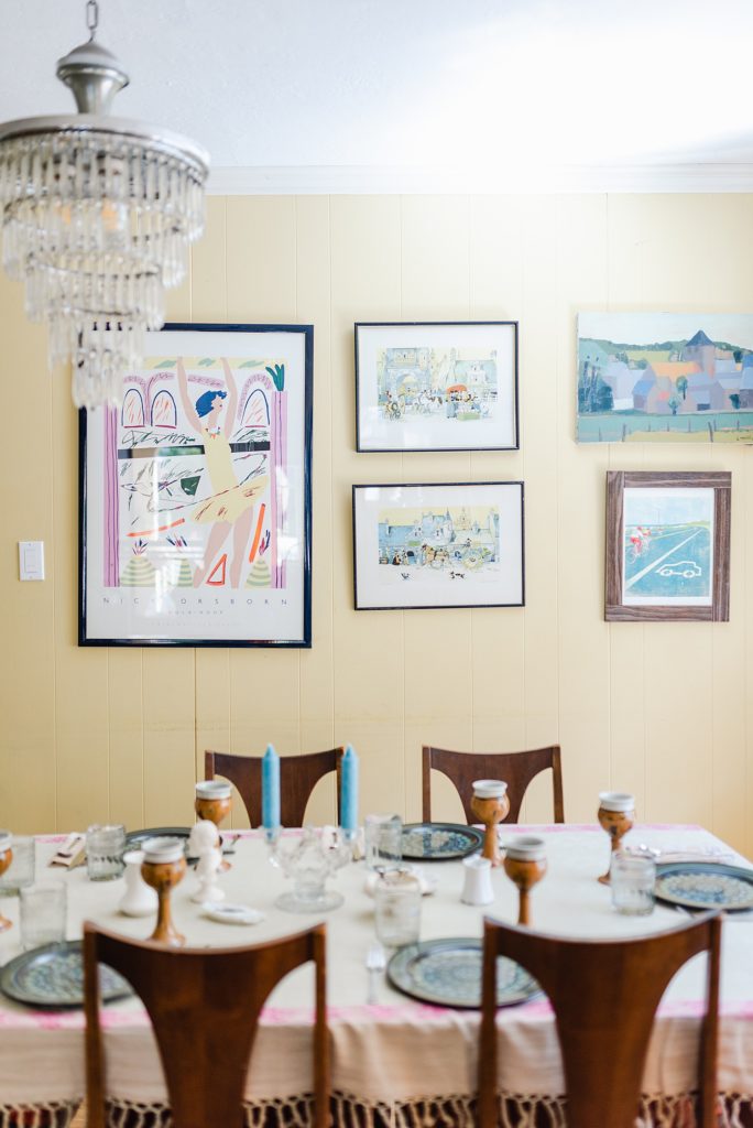dining area with sketch arts on the yellow walls. the dinner table is arranged with a formal table setting