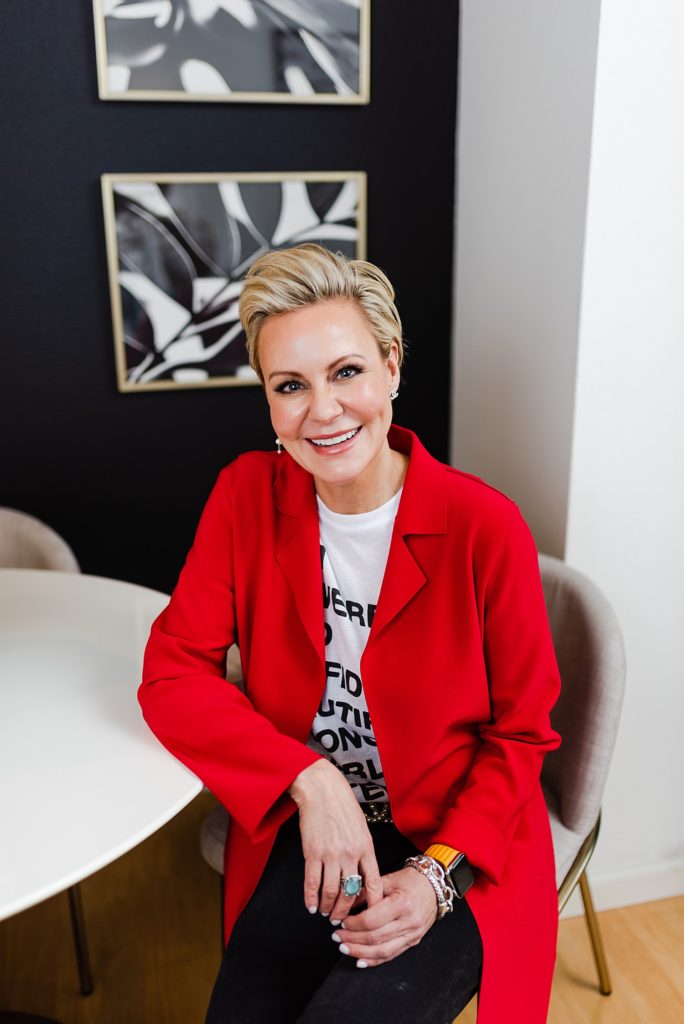 Portrait of a woman wearing a red blazer while sitting by a white round table