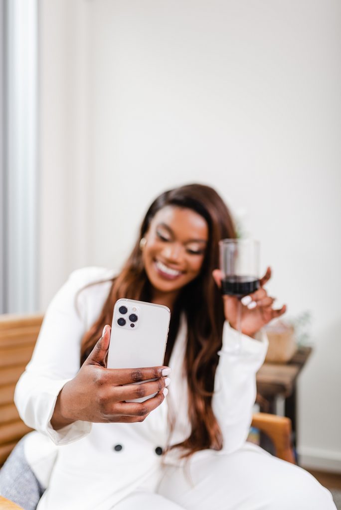 woman in white is taking a selfie with a glass of wine