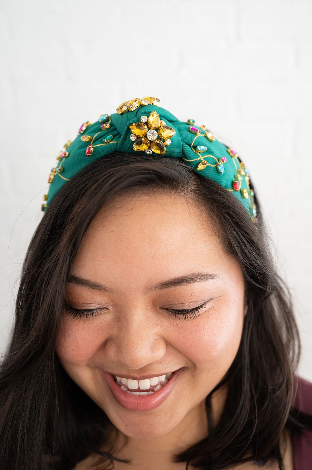 A smiling woman wearing a green headband. She's looking downwards.