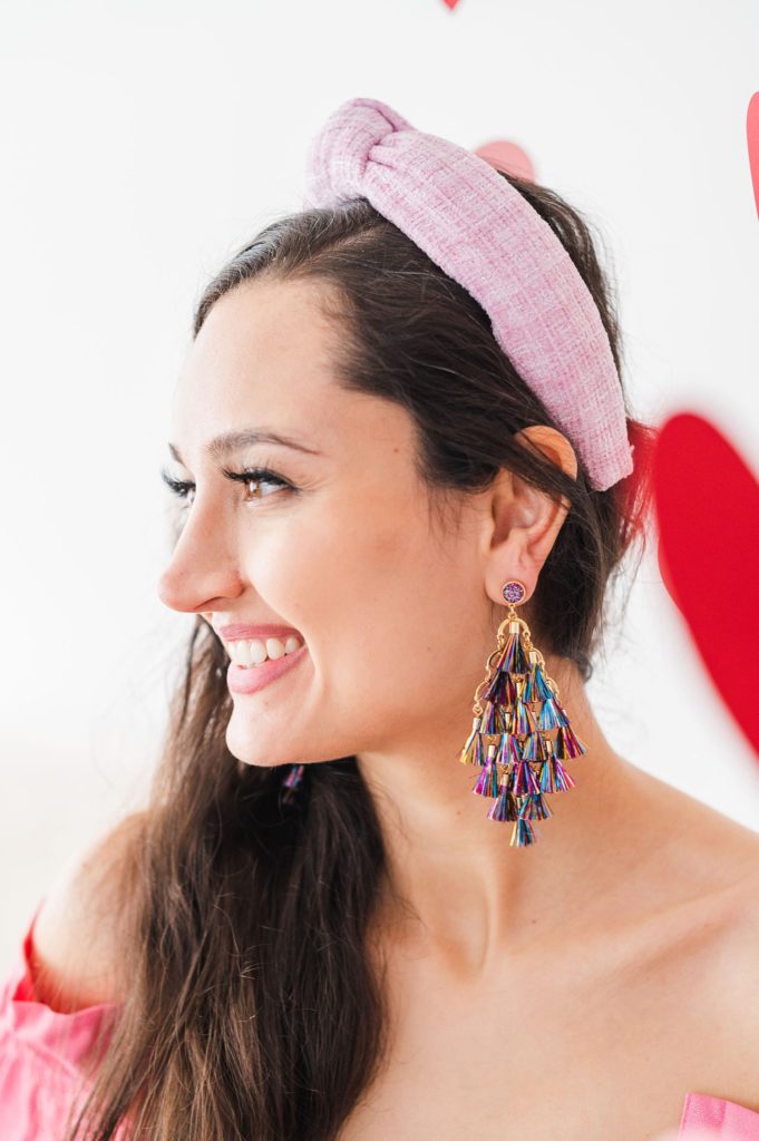 ballerina tweed headband and tassel chandelier drop earrings on a model. the model is in a bubblegum pink dress and there are hearts hanging from the ceiling