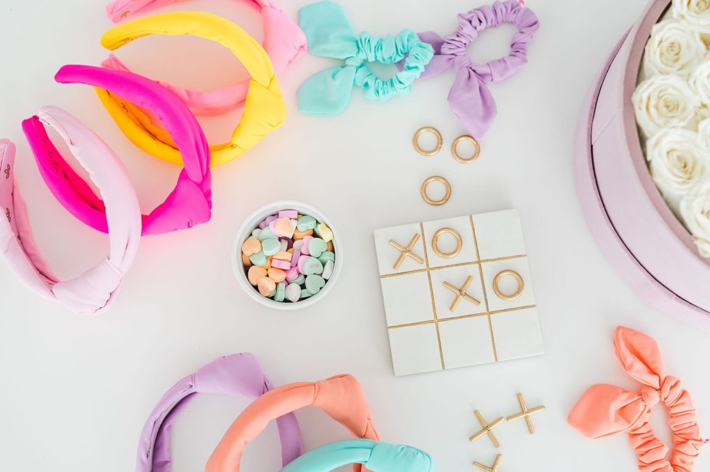flat lay of pastel neoprene headbands. there is a tic tac toe board and the pieces are arranged to say "XOXO"