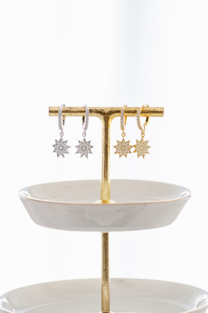 two pairs of 9 point star Bahai earrings hanging on a jewelry holder.