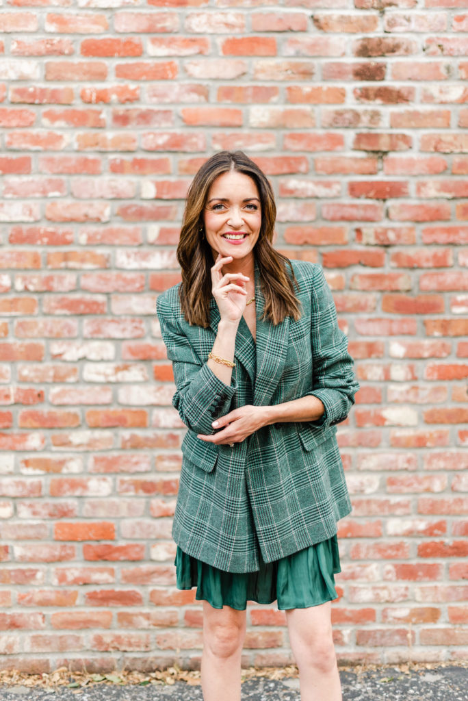 Woman Standing in front of a Brick Wall in Green Blazer