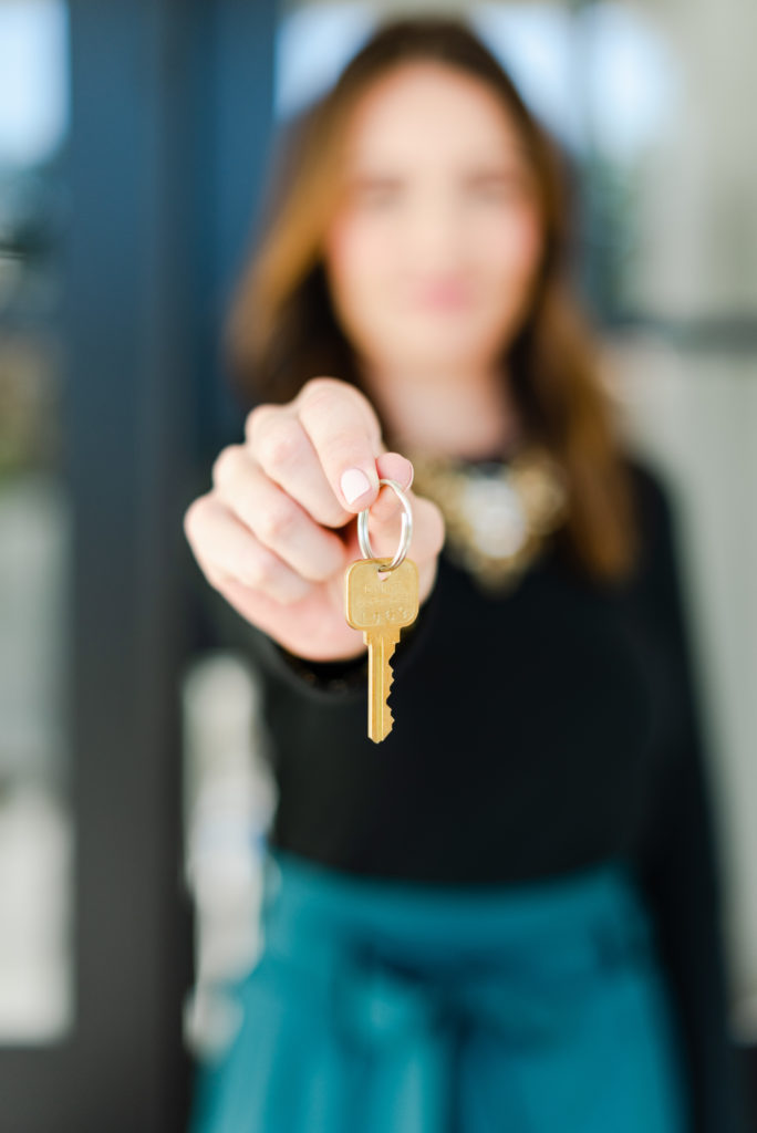 Realtor holding out a key to a home