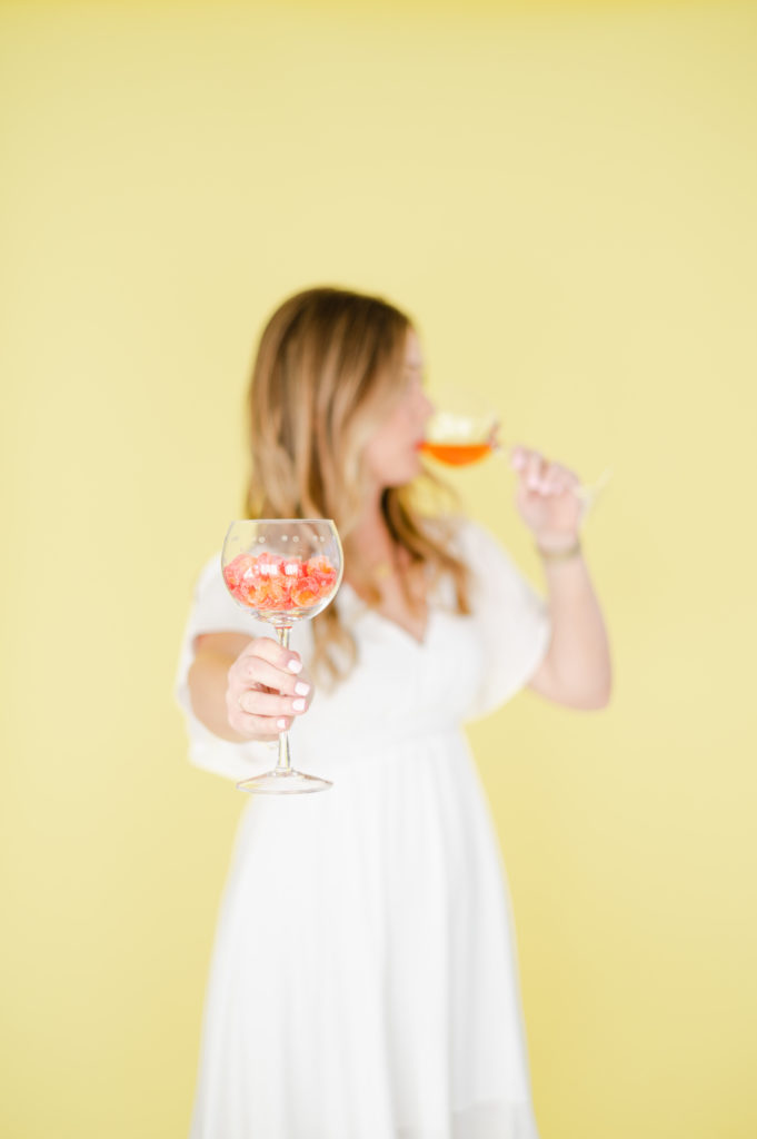 Woman taking a sip of wine out of focus, while holding out a glass of wine. 
