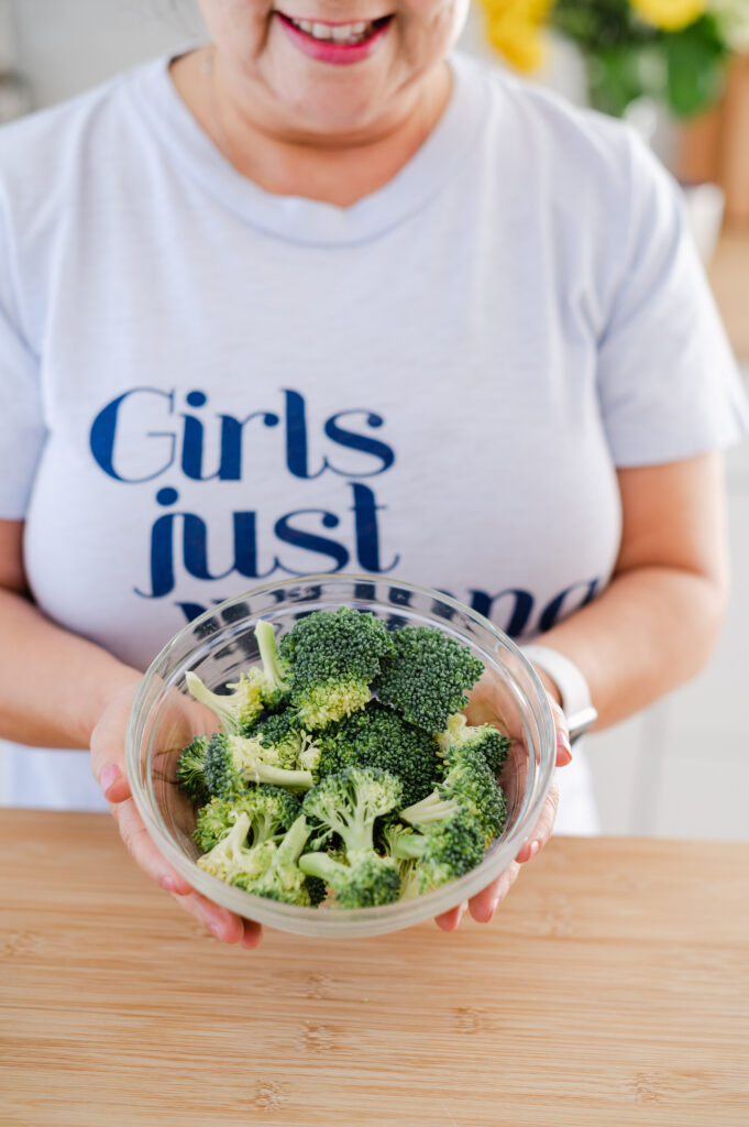 Close up of woman holding bowl of fresh broccoli