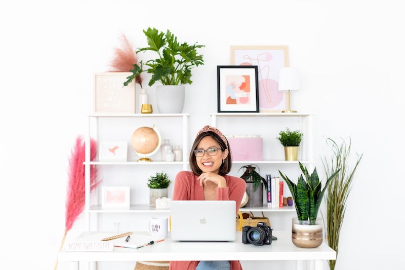 brand photographer sitting at a desk with colorful shelves in the background