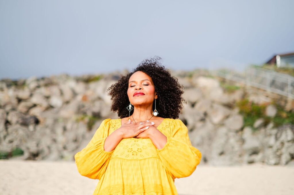 woman with hands over her heart on the beach