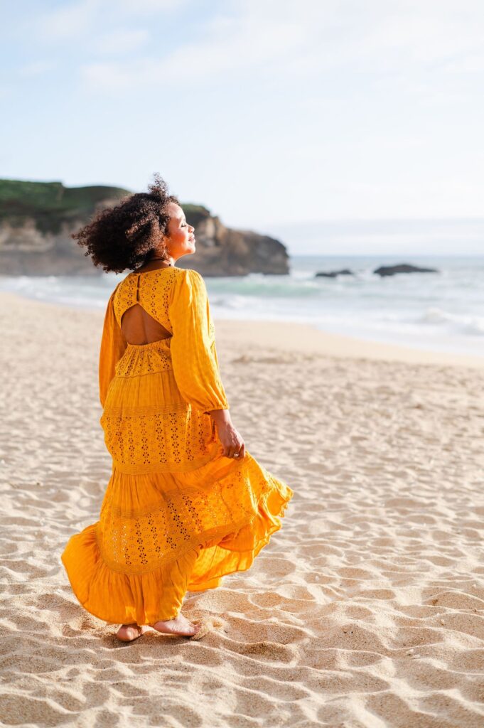 woman with a flowy yellow dress on the beach